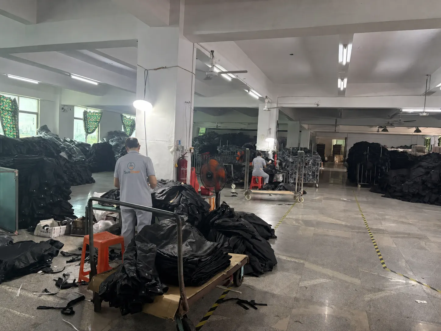 SunCheer staff checking black jacket components on the factory floor